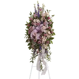Tall floral standing spray with pink and lavender flowers on a white easel