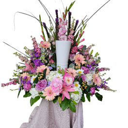 Large pink and purple floral arrangement in a white pedestal vase