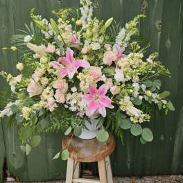 Large pastel floral arrangement in a white vase with pink lilies and roses