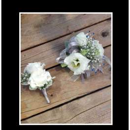 White floral corsage and boutonniere with ribbon on wood