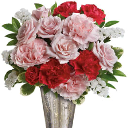Pink roses and red carnations with white filler flowers arranged in a silver metallic vase.