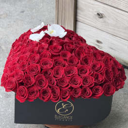 Heart-shaped box of red roses with white orchids on top