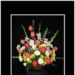 Arrangement of coral roses, white flowers, and yellow daisies in a vase