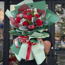 Bouquet of red roses with holiday ornaments and green wrapping