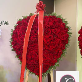 Heart-shaped red rose standing spray with a ribbon on an easel