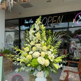 Tall white and pale yellow floral arrangement in a white vase