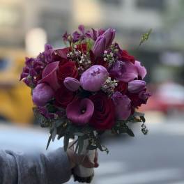 Handheld bouquet of purple and red flowers with a wrapped stem