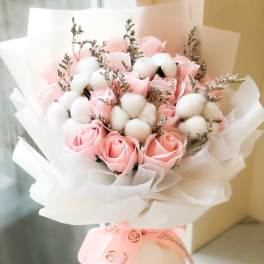 Pink roses and white cotton stems in a wrapped bouquet
