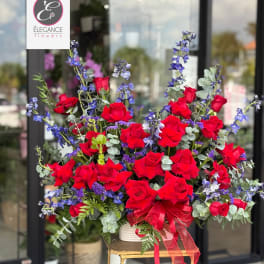 Large bouquet of red roses and blue flowers with a red ribbon