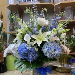 Blue and white floral arrangement with lilies, hydrangeas, and calla lilies in a gift box