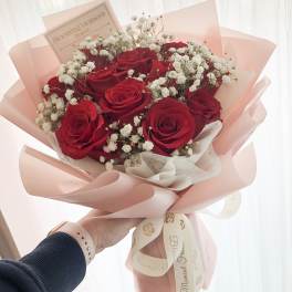 Bouquet of red roses and white baby's breath wrapped in pink paper