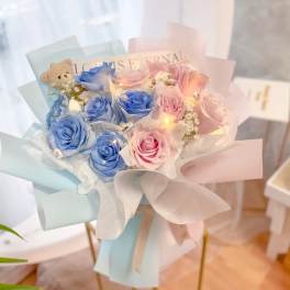 Bouquet of blue and pink roses with a small teddy bear