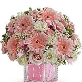 Pink gerbera and roses in a clear cube vase with a pink monogram