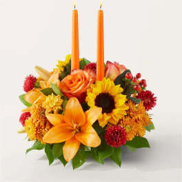 Orange floral centerpiece with two orange candles