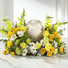 Yellow and white floral arrangement around a silver urn
