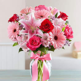Pink and red mixed bouquet in a glass vase with a pink ribbon
