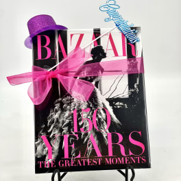Gift-wrapped Harper's Bazaar 150 Years book with a purple hat and pink ribbon
