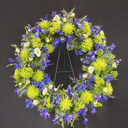 Circular floral wreath with blue and lime-green flowers on a stand