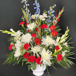 Red, white, and blue floral arrangement in a white vase