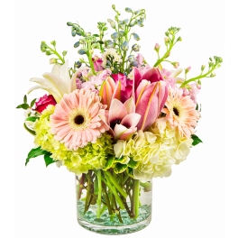 Mixed arrangement of pink lilies, gerbera daisies, and hydrangeas in a clear glass vase