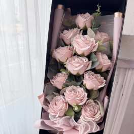 Bouquet of pale pink roses in a black gift box with ribbon