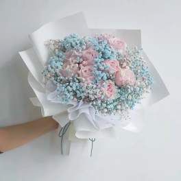 Bouquet of pink roses with blue baby's breath in white paper