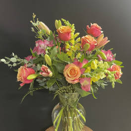 Bouquet of pink and peach roses with lilies in a clear glass vase