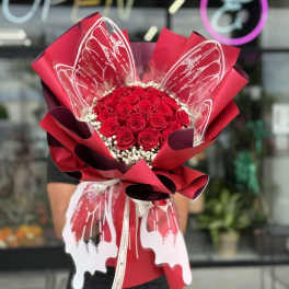 Bouquet of red roses wrapped in red paper with white accents
