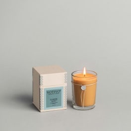Lit amber candle beside its boxed packaging