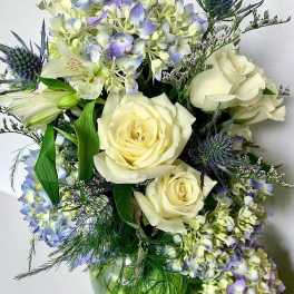 Bouquet of cream roses and pale blue flowers with greenery
