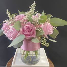 Pink roses in a clear glass vase with eucalyptus and filler flowers