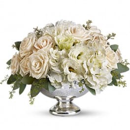 Low centerpiece of cream roses and white hydrangeas in a silver pedestal bowl