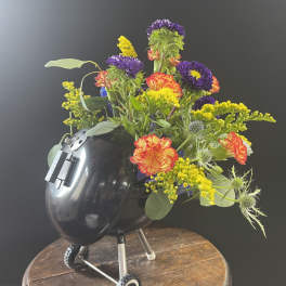 Colorful flower arrangement in a black helmet-shaped container