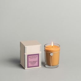 Lit amber candle in a glass tumbler beside its box