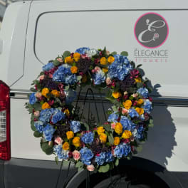 Large floral wreath with blue hydrangeas and yellow roses on a stand