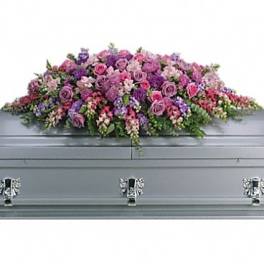 Pink and purple floral casket spray on a gray casket