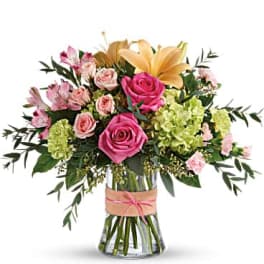 Bouquet of pink roses, lilies, and green hydrangeas in a glass vase