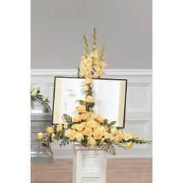 Yellow floral arrangement around an open Bible on a stand