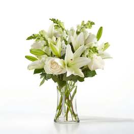 White lilies and roses arranged in a clear glass vase