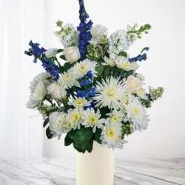 White and blue floral arrangement in a cream vase