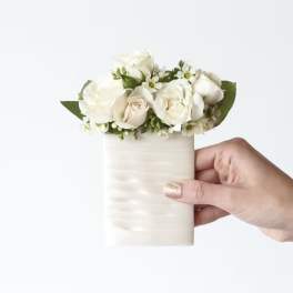 Small white rose arrangement in a cream cylindrical vase