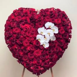 Heart-shaped arrangement of red roses with white orchids