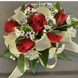 Red rose wrist corsage with white filler flowers and gold ribbon loops