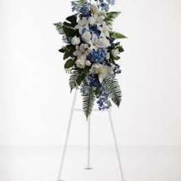 Blue and white funeral spray on a white easel