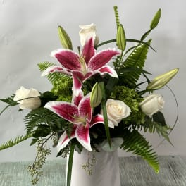 Pink stargazer lilies and white roses in a white vase