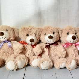 Four plush teddy bears with ribbon bows sitting in a row