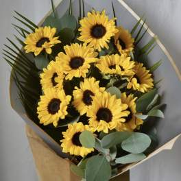 Bouquet of yellow sunflowers wrapped in gray paper