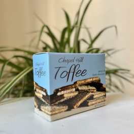 Box of Chapel Hill toffee on a table with a plant in the background