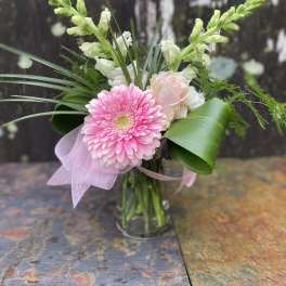 Pink gerbera bouquet in a glass vase with white blooms and ribbon