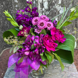 Purple and pink bouquet in a glass vase with a ribbon